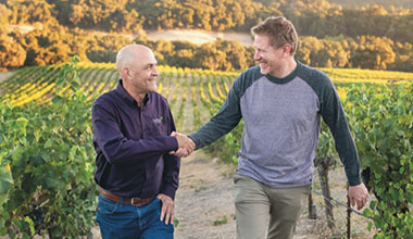 Two men shaking hands in a vineyard